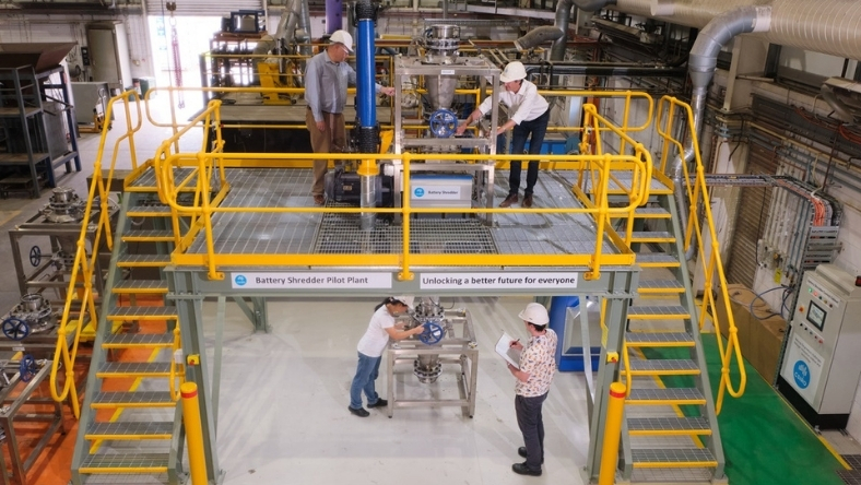 Engineers operating battery recycling pilot plant on elevated industrial platform